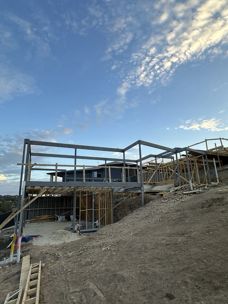 Steel frame erected above a sloping building site at Diamond Creek