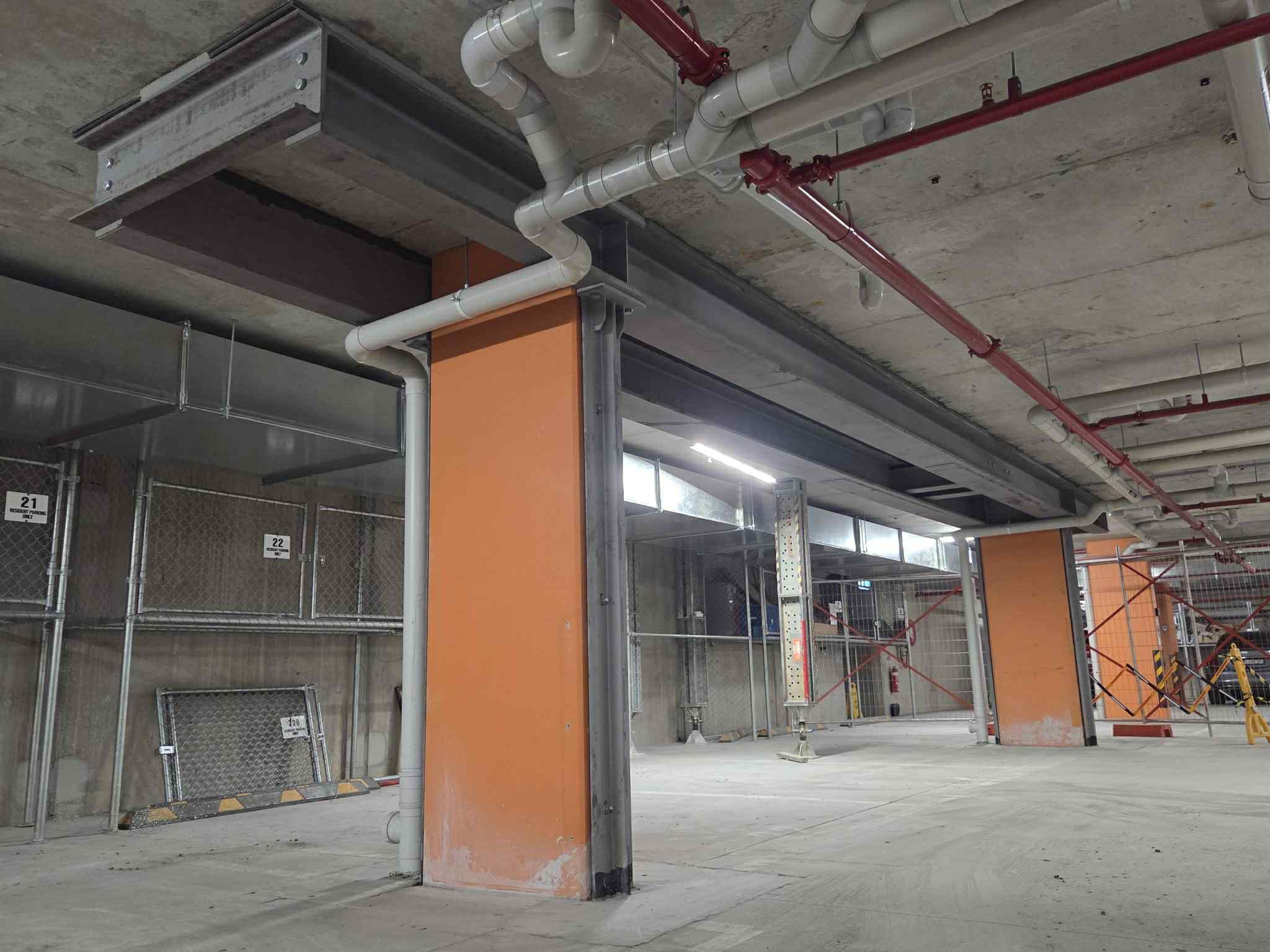 Close view of an overhead steel beam and column beside an orange pier at Glen Waverley