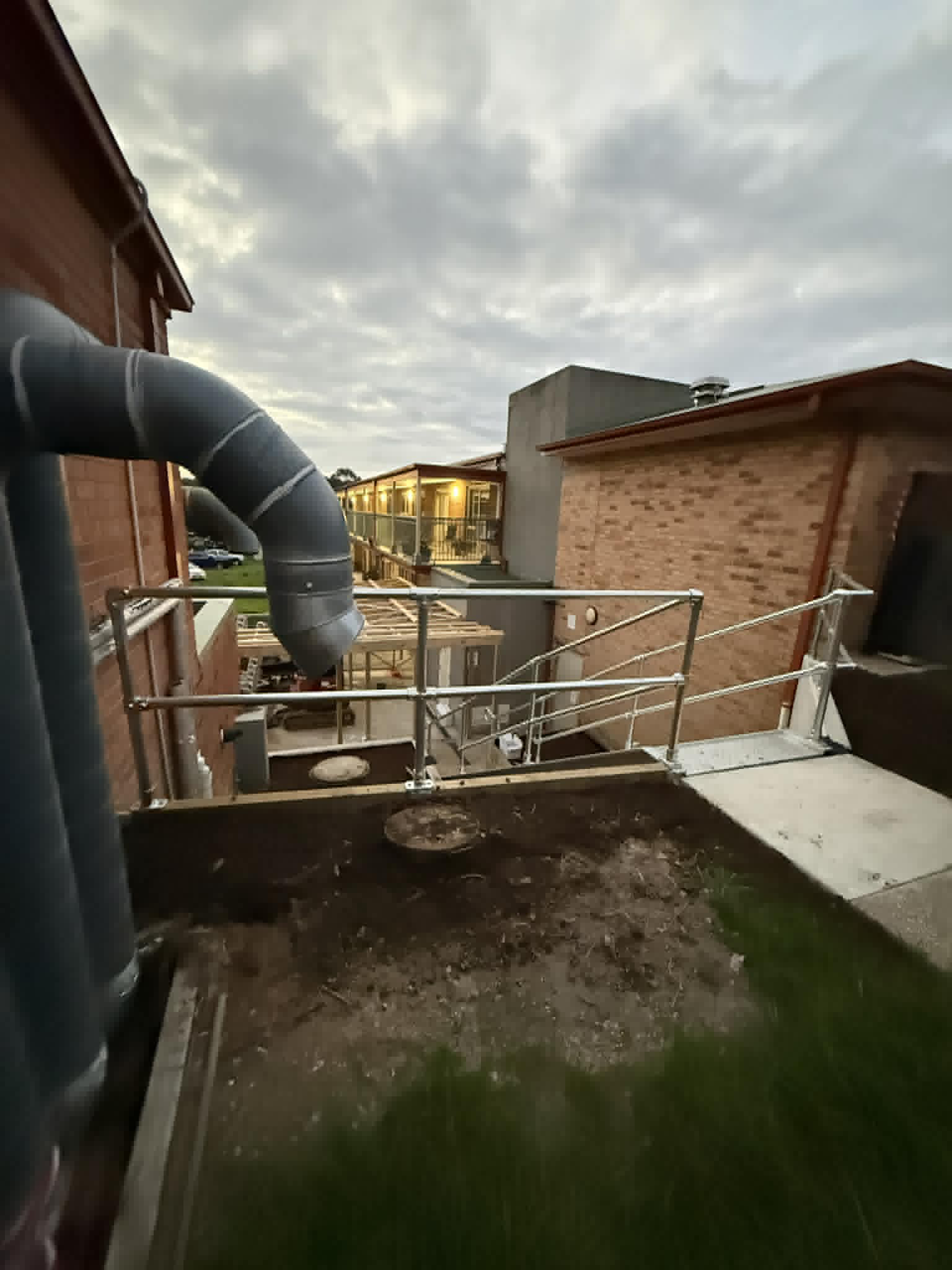Steel access walkway and handrails beside brick buildings at Kalimna